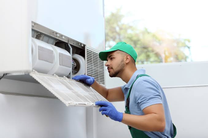 HVAC technician servicing a wall-mounted air conditioning unit