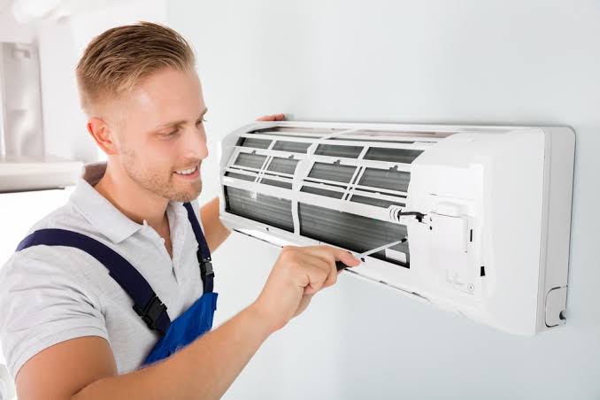 Technician servicing a wall-mounted residential air conditioning unit