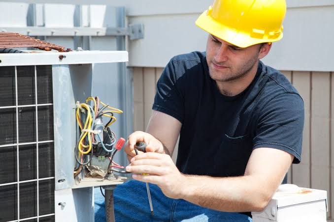 HVAC technician inspecting residential outdoor air conditioning equipment