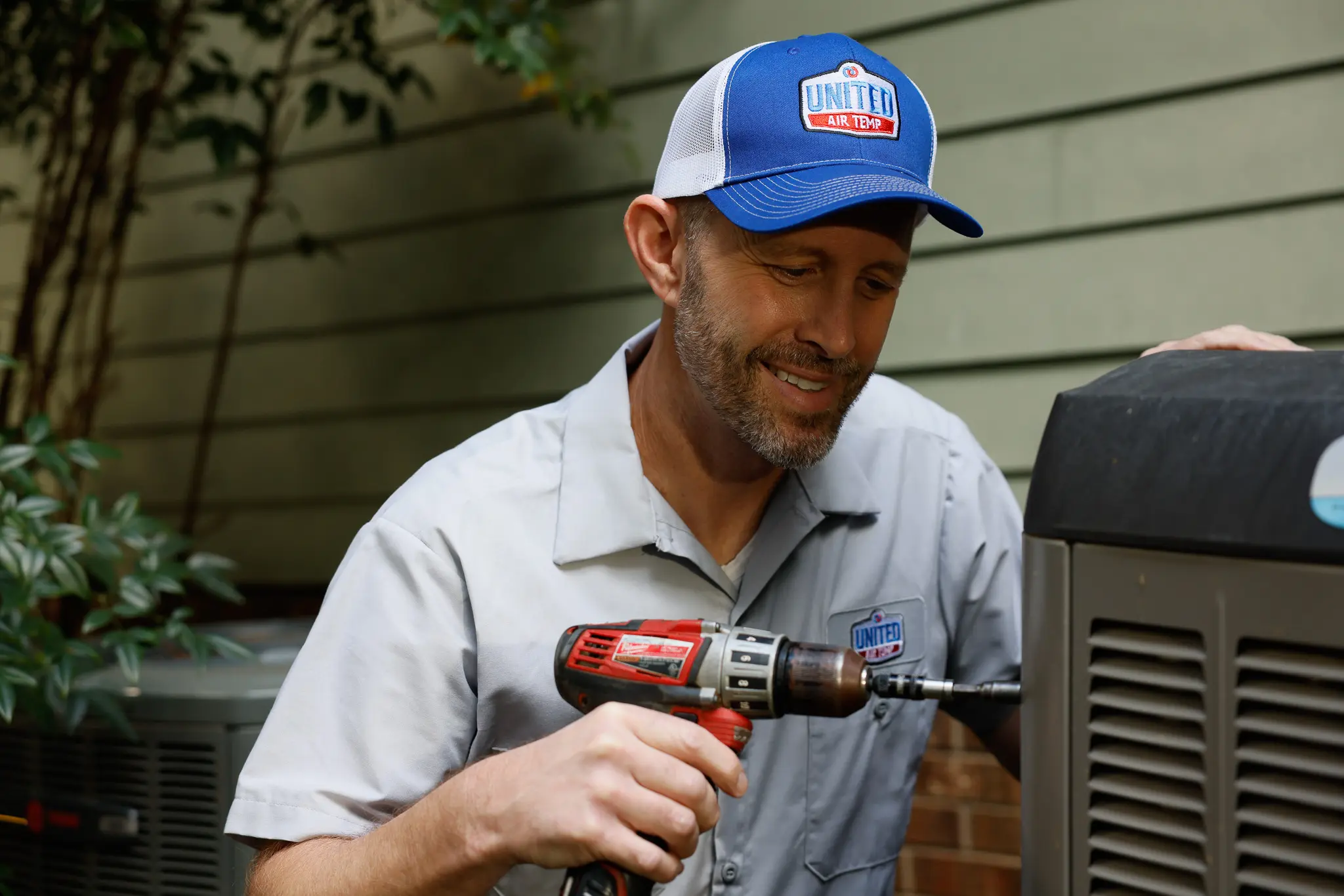 Technician performing detailed maintenance on outdoor HVAC equipment